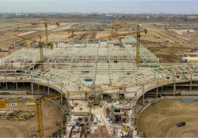 Vista aérea de una gran obra en construcción con numerosas grúas y trabajadores