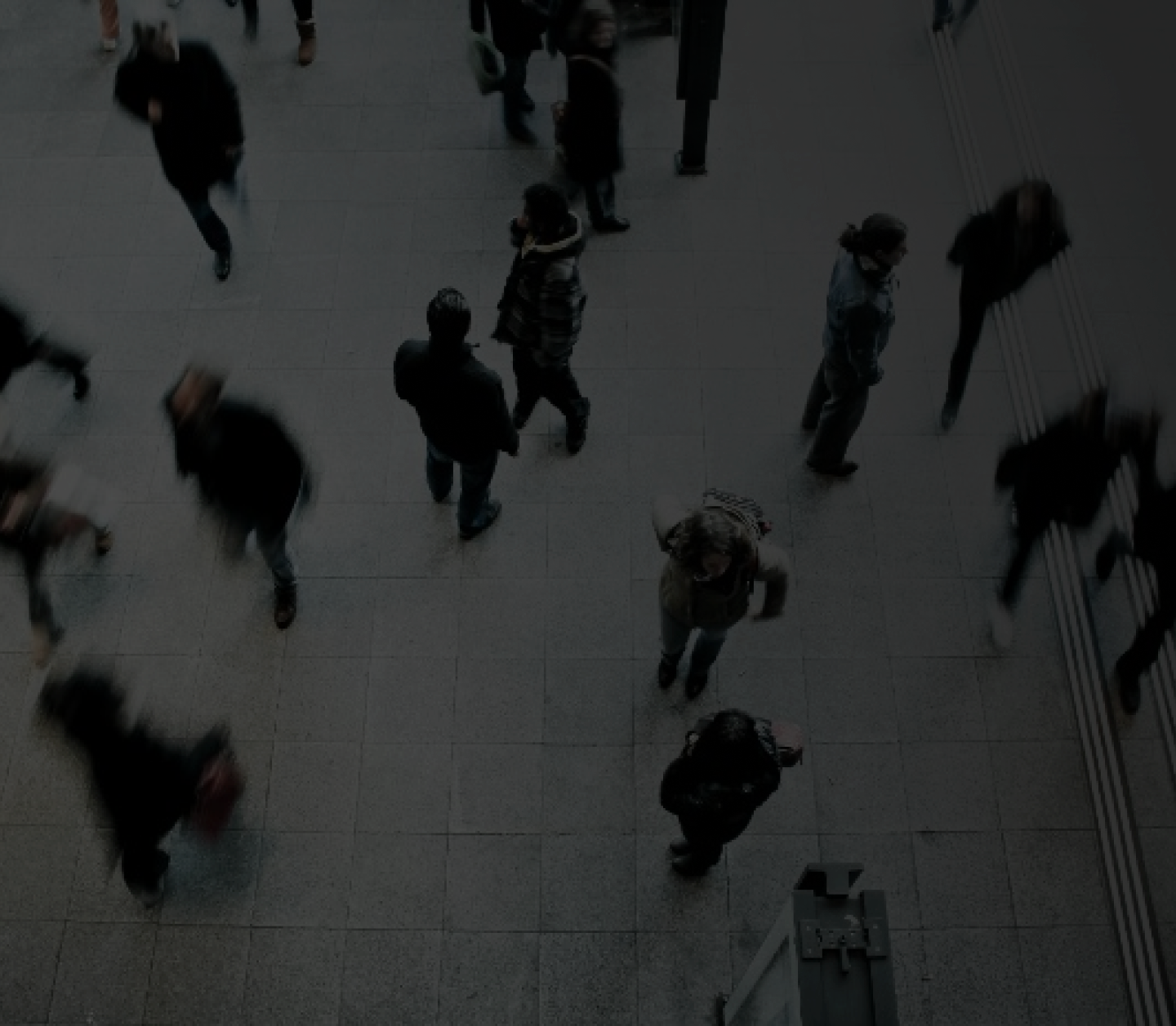 Blurred motion of various people walking on a dimly lit indoor floor